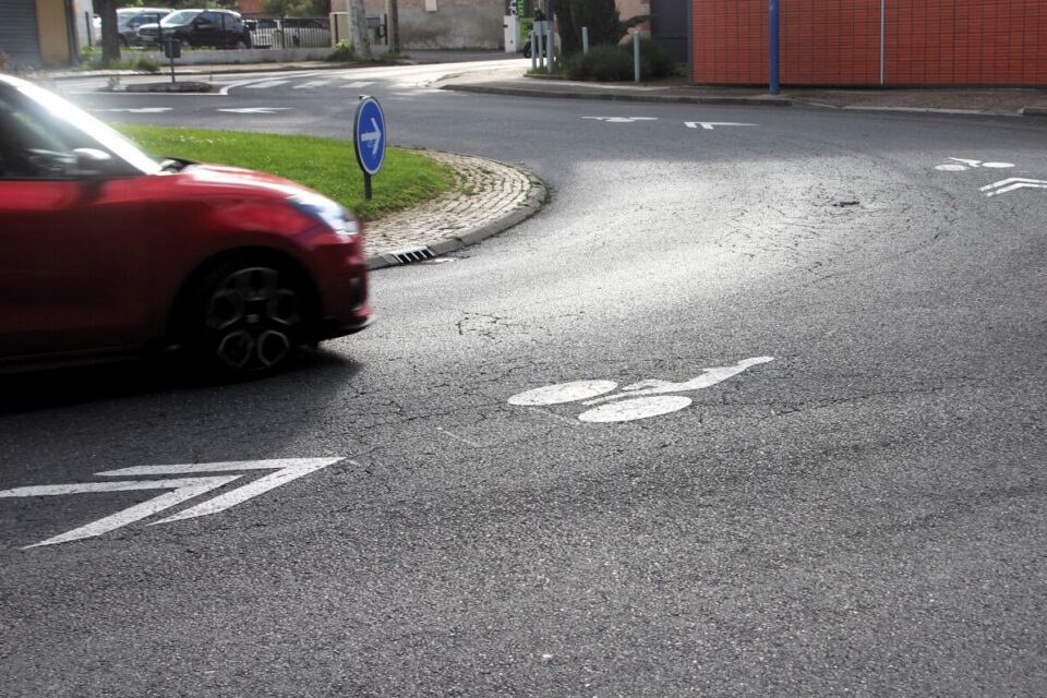 Photo d'un rond-point avec un chemin cyclable (chevrons et pictogramme vélo au sol) au milieu de la voie